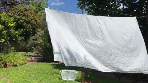 White bed sheets drying on a rotary clothesline Stock Footage 344889264
