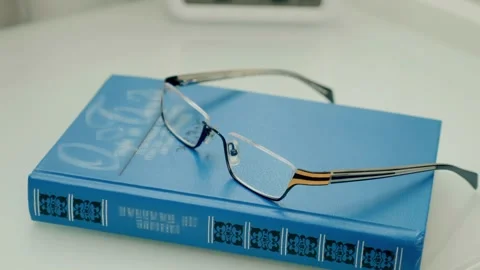 On the white bedside table with the clock there is a blue book and glasses  Stock Footage 297804729