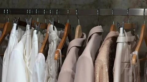 White beige range of clothes hangs on hangers in boutique Stock Photos
