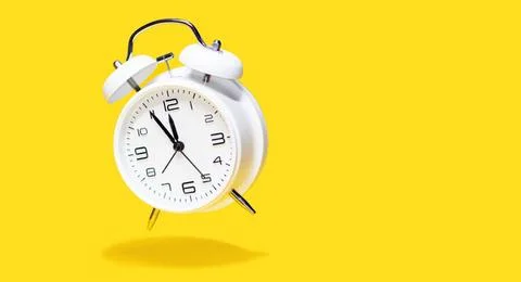 White bell alarm clock hovering over yellow background. 5 to 12 clock conc... Foto stock