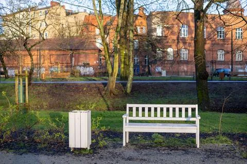 A white bench and a garbage dump in the spring city park. Stock Photos