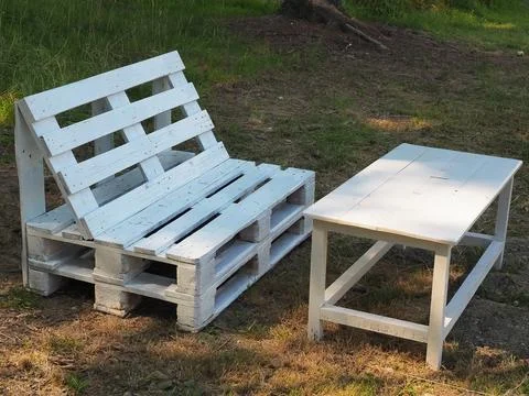 White bench and table from old wooden storage pallets stand on the ground with Stock Photos