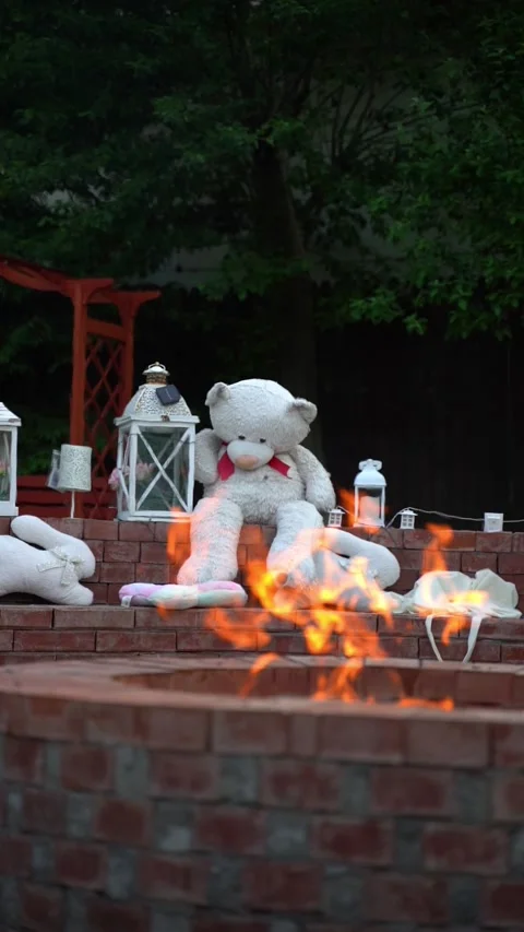 White big teddy bear with lanterns behind a fire outside Stock Footage 314056122