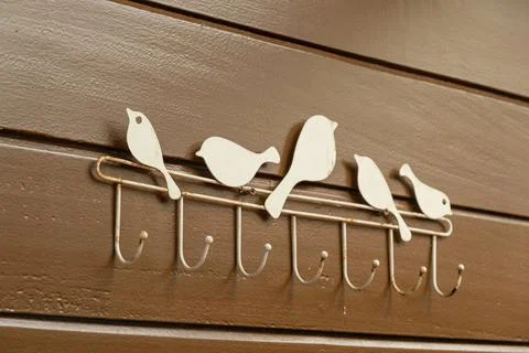 White bird coat rack with hooks on brown wooden wall Stock Photos