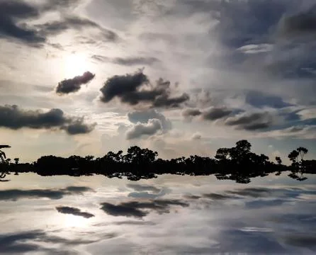 White black clouds in the blue sky and shadows of clouds in the water. Stock Photos