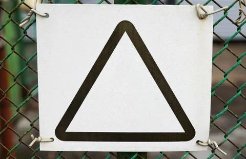 A white blank with a black triangle on a mesh fence, a paper sheet is screwe Stock Photos