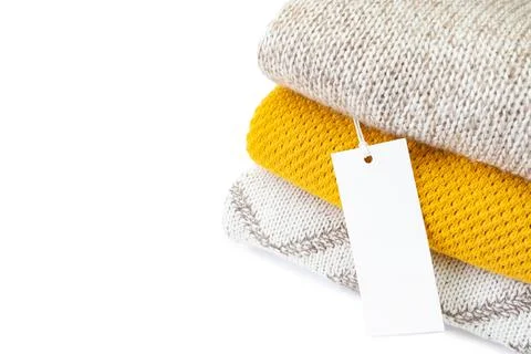 White blank clothing tag on stack of knitted clothes isolated on white 스톡 사진