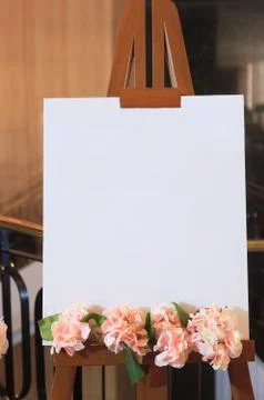 White blank empty canvas frame with flower decoration on wooden stand backgro Stock Photos