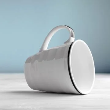 White blank mug lying on side on white wooden table and blue background Stock Photos