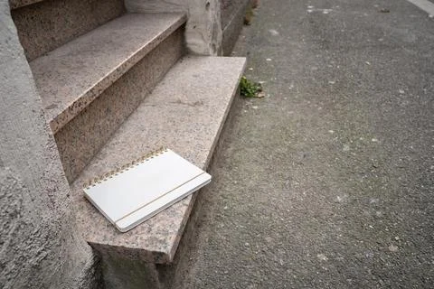 White blank notebook lying on the bottom step outside Stock Photos