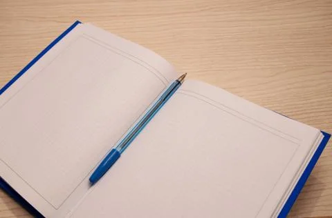 White blank notepad to the writing cage lies on a wooden background with a bl Stock Photos