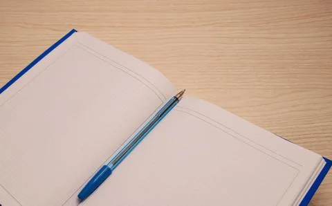 White blank notepad to the writing cage lies on a wooden background with a bl Stock Photos