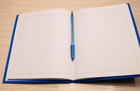 White blank notepad to the writing cage lies on a wooden background with a bl Stock Photos