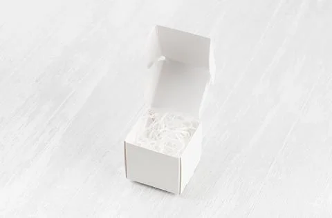 White blank open square box with paper filler mock up on wood board side view Stock Photos