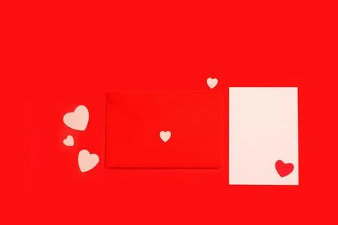 A white blank paper, a red envelope and paper hearts on a red background Stock Photos