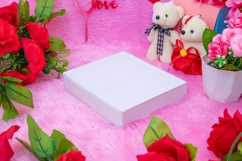 White blank rectangle box above a fluffy pink carpet surrounded by dolls an.. Stock Photos