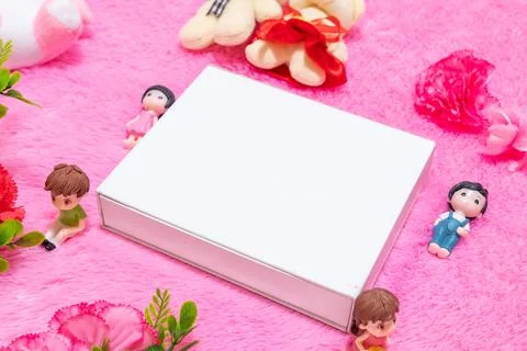 White blank rectangle box above a fluffy pink carpet surrounded by dolls Stock Photos