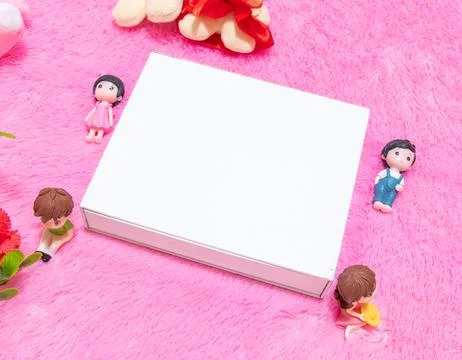 White blank rectangle box above a fluffy pink carpet surrounded by dolls Stock Photos