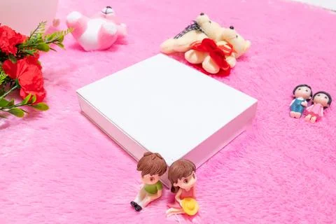 White blank rectangle box above a fluffy pink carpet surrounded by dolls Stock Photos