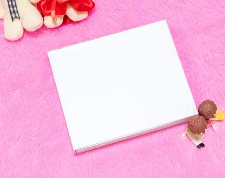 White blank rectangle box above a fluffy pink carpet surrounded by dolls Stock Photos