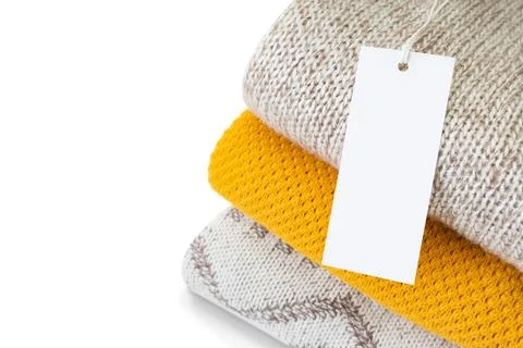 White blank rectangular clothing tag on stack of knitted clothes isolated on 스톡 사진