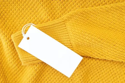 White blank rectangular clothing tag, label mockup template on yellow knitted Stock Photos