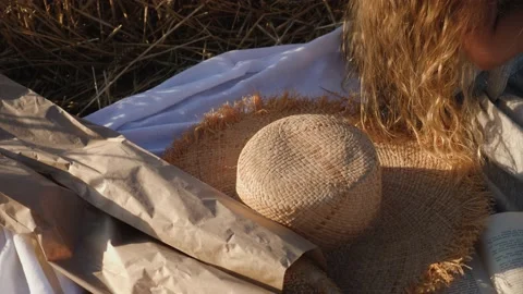 On a white blanket lies fresh bread in a bag and a hat and a gir Video stock 135790488