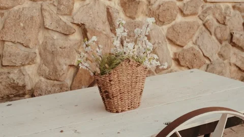 White Blossom Branches in a Woven Basket on a White Wooden Table Stock Footage 344013357