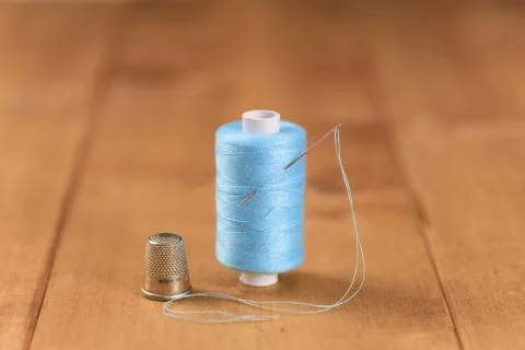 White blue cotton thread bobbin with needle close up Stock Photos