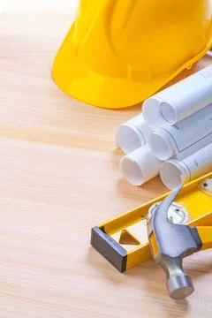 White blueprints construction level yellow helmet claw hammer on wooden boa.. Stock Photos