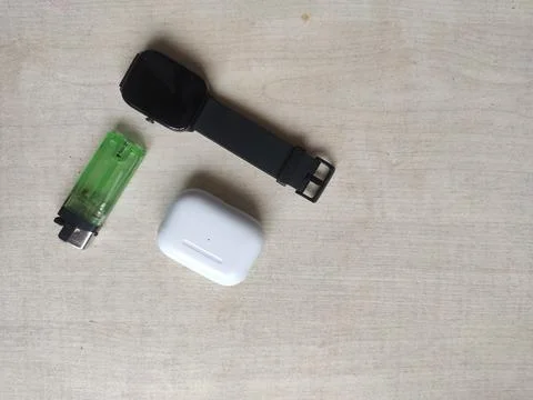 White bluetooth headset, black digital watch, and green lighter 스톡 사진