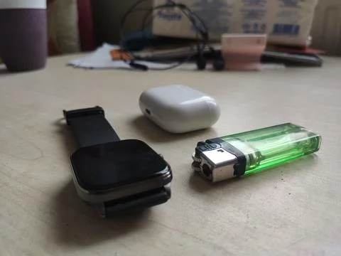 White bluetooth headset, black digital watch, and green lighter Stock Photos