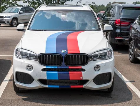 A white BMW SUV with multi colored stripes on the hood parked in a lot Stock Photos