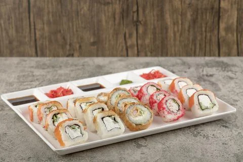 A white board with different types of delicious sushi rolls on stone table Stock Photos