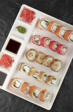 A white board with different types of delicious sushi rolls on black table Stock Photos