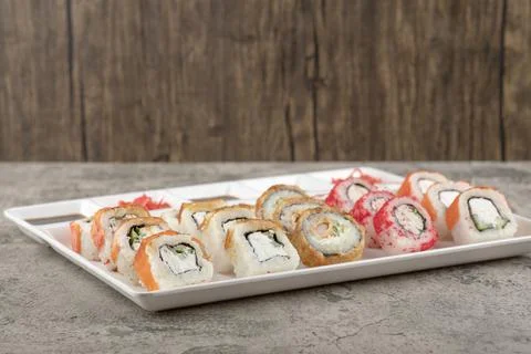 A white board with different types of delicious sushi rolls on stone table Stock Photos