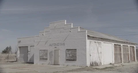 White Boarded Up Abandoned Gas Station in Desert - Three Quarter View Stock Footage 89942780