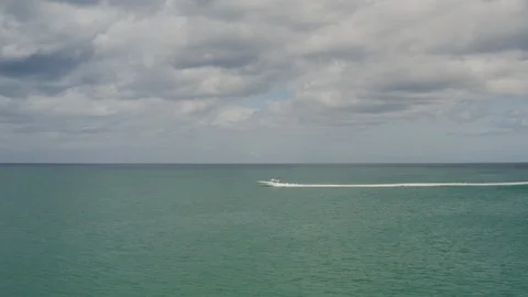 White boat heading up to calm empty turquoise  ocean under clouded sky Stock Footage 126613002