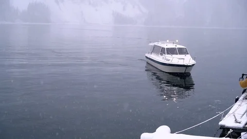 White boat with people on board moor to pier, alpine cold winter lake, snowing Stock Footage 115959853