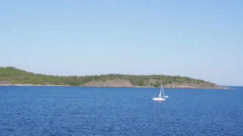 White boat sailing from left to right on the ocean in front of island Stock Footage 159093242