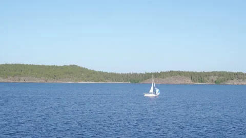 White boat sailing from left to right on the ocean in front of island Stock Footage 159131845