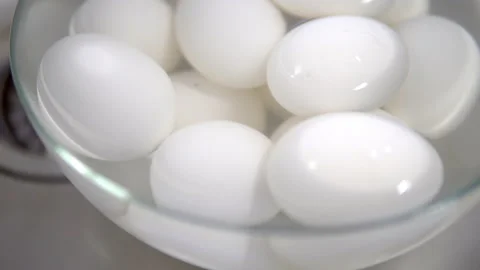 White boiled chicken eggs lie in a plate of water and cooled Stock Footage 153909577