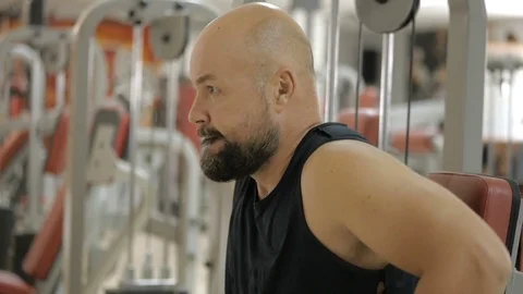 White bold bearded man is doing dips exercise on a machine in gym Stock Footage 79538897