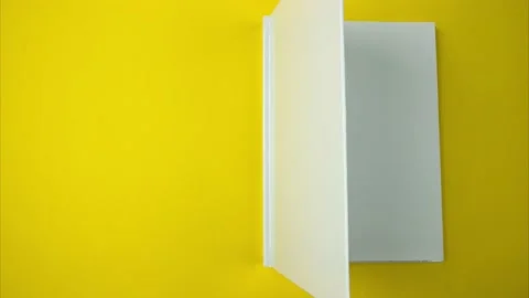 White book appears quickly rotating on a yellow background. Stock Footage 169657669