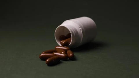 White Bottle with Brown Capsules and Vitamins Spilling Out Stock Footage 342237672