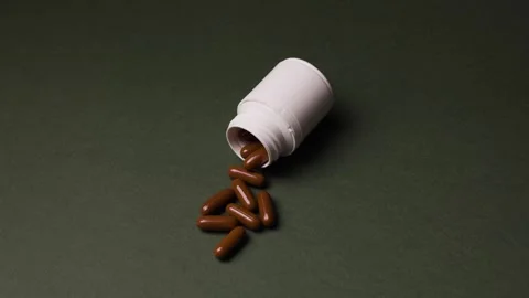 White Bottle with Brown Capsules and Vitamins Spilling Out Stock Footage 342237692