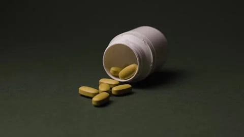 White Bottle with Capsules and Vitamins Rotating on Green Background Stock Footage 342237661