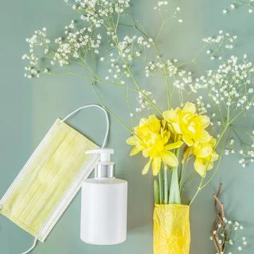 White bottle with cosmetic product for hand care, medical mask and daffodils Stock Photos