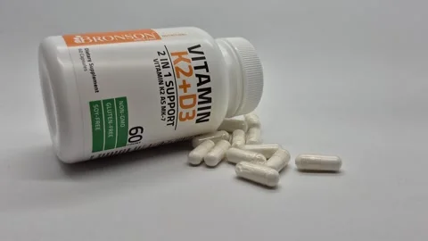 White bottle of Vitamin K2 plus D3 supplements with capsules Stock Footage 345269177