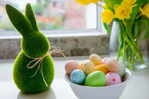 White bowl with colored easter eggs, bouquet of yellow tulips and daffodils Stock Photos
